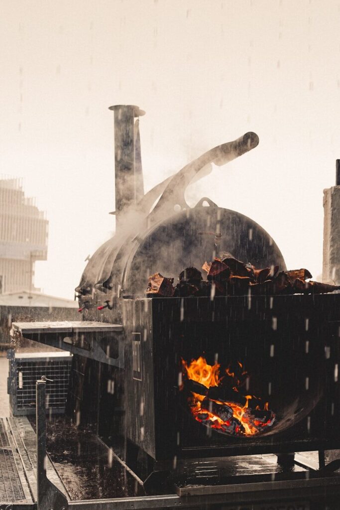 Photo by Letícia Fracalossi a man standing next to a large oven on top of a roof