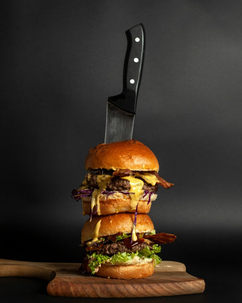 pexels-photo-4809158-4809158 Vertical shot of a double cheeseburger stacked on a wooden board with a knife, perfect for gourmet food themes.